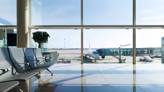 Foto: Blick aus einem Flughafen-Terminal auf das Vorfeld und die Startbahn