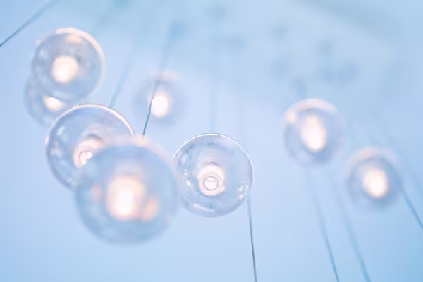 Mehrere runde, gläserne Deckenleuchten hängen an dünnen Kabeln und leuchten in einem weichen, bläulichen Licht.